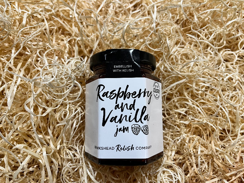 Jar of raspberry and vanilla jam on a bed of straw