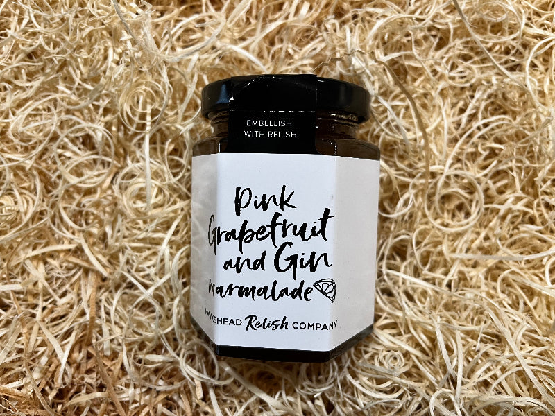 Jar of pink grapefruit and gin marmalade on a straw background