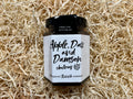 Jar of apple, date, and damson chutney on a textured beige background