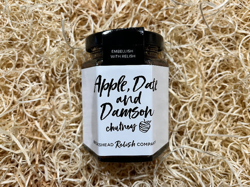 Jar of apple, date, and damson chutney on a textured beige background