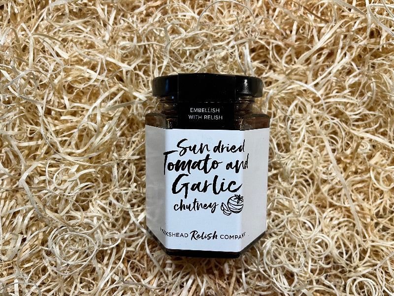 Jar of sun-dried tomato and garlic chutney on a rustic background