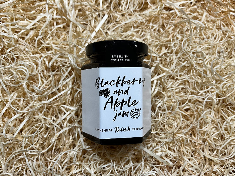 Jar of blackberry and apple jam on a bed of straw