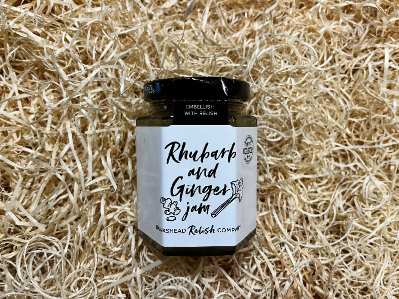 Jar of rhubarb and ginger jam on a bed of straw