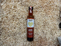 Bottle of Drizzle & Company Cajun Sauce on a bed of straw