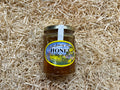 Jar of honey with a label on a bed of straw