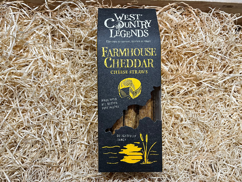 West Country Legends Farmhouse Cheddar Cheese Straws packaging on a bed of straw.