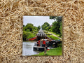 Narrowboat on a canal with a lock, framed by straw-like material