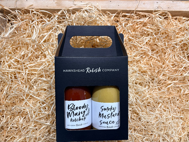 Two bottles of sauce in a black carrying box on straw
