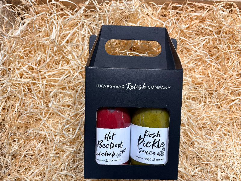 Two bottles of Hawkshead Relish Company sauces in a black box on straw.